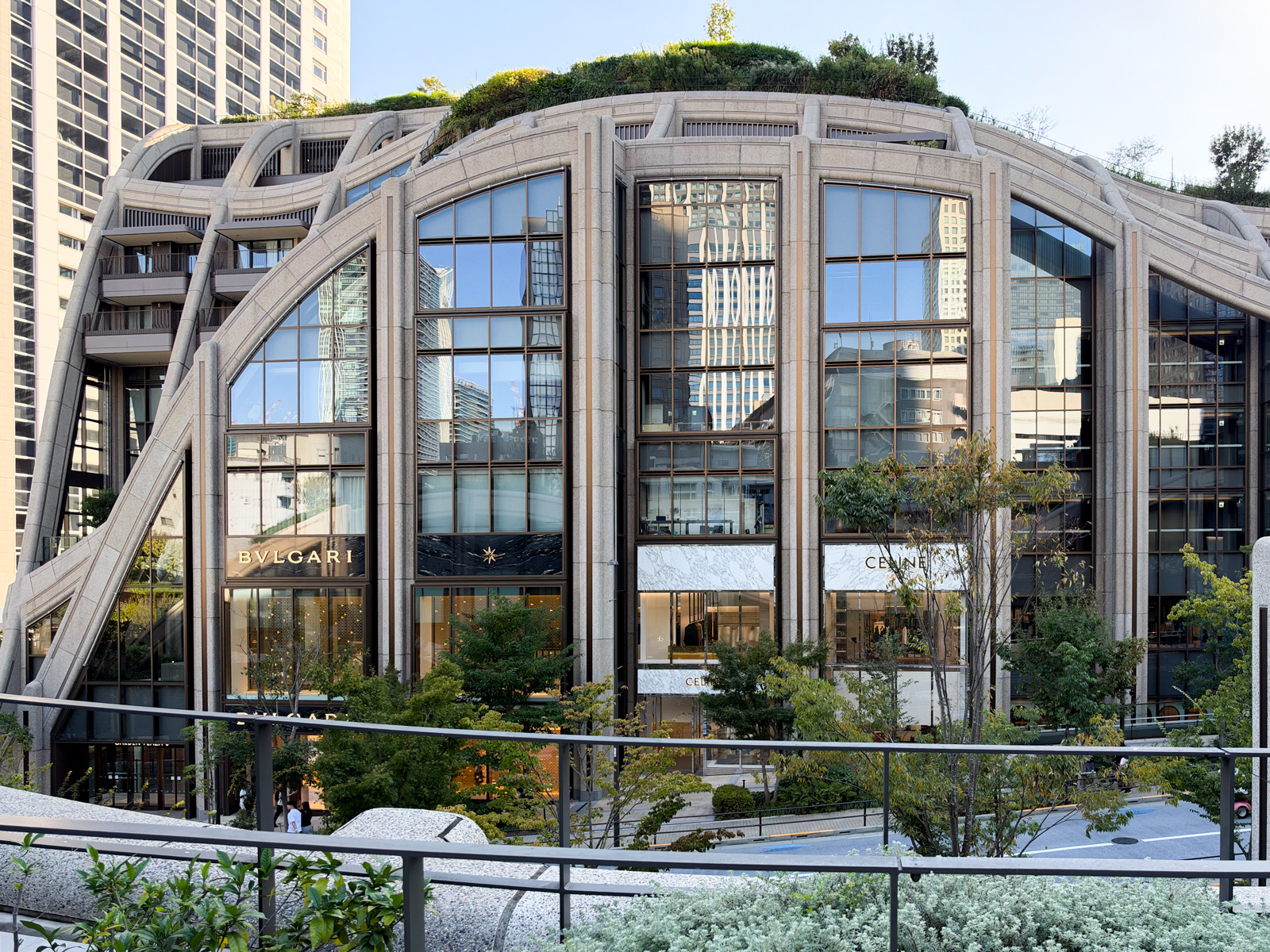 Heatherwick Studio設計の低層商業棟「The Gardens」。ポルトガル産石灰岩のアーチが複数組み合わさり、屋上には植栽が茂る。遠景に森JPタワー